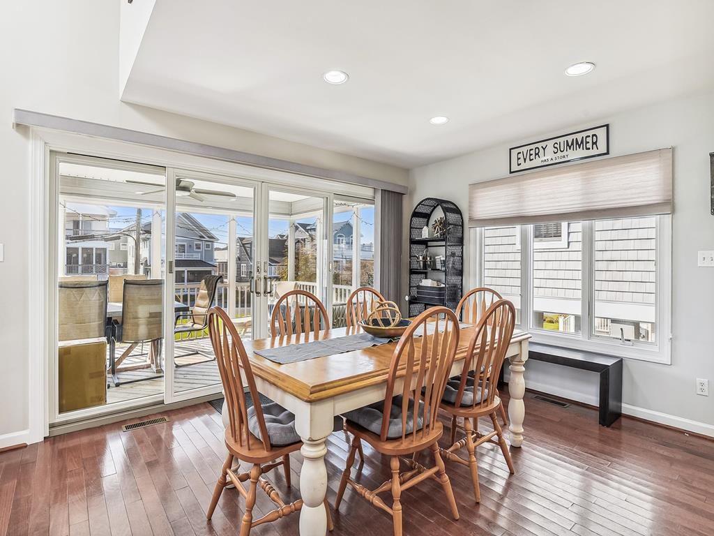 A dining area with a wooden table and chairs, a bench, and a view through large glass doors.