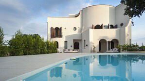 A modern building with a pool, featuring a curved facade, arched windows, and a balcony. - Marina dei Greci (Giardini Naxos)
