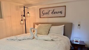 A neatly made bed with a white duvet and two white pillows, a wall-mounted light fixture, and a framed sign that reads "Sweet dreams". - Downtown SLC 1BR · Marmalade · Walk to Capitol (Salt Lake City)