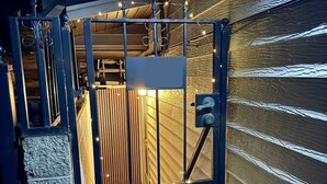 A gated garage entrance with a metal gate, a wooden door, and a small sign above the door. - Downtown SLC 1BR · Marmalade · Walk to Capitol (Salt Lake City)