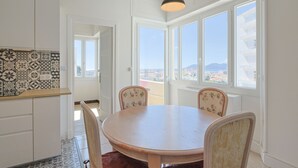 A dining area with a round table and chairs, large windows with a view, and patterned tile backsplash. - L Horizon in Cannes With 2 Bedrooms and 1 Bathrooms (Cannes)