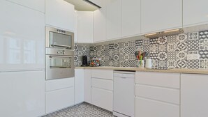 A modern kitchen with white cabinets, a stainless steel oven, a dishwasher, and patterned backsplash tiles. - L Horizon in Cannes With 2 Bedrooms and 1 Bathrooms (Cannes)
