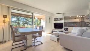 Un soggiorno moderno con zona pranzo, divano, televisione e cucina sullo sfondo.