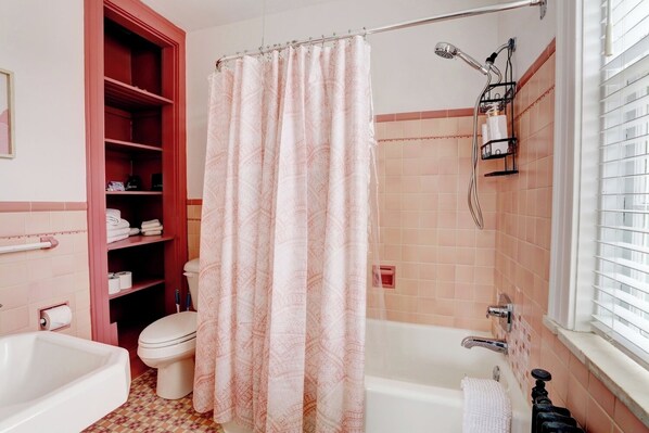 A bathroom with a bathtub, toilet, and shower area.