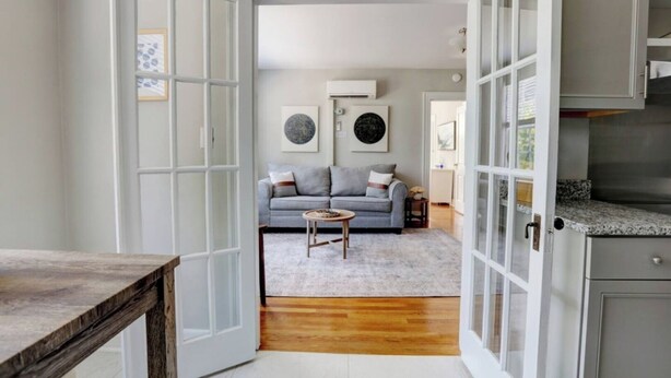 A spacious living room with a grey sofa, a coffee table, and a rug. There are two doors leading to other rooms. - Historic Building/Walkable to Dtown/Central (Frankfort)