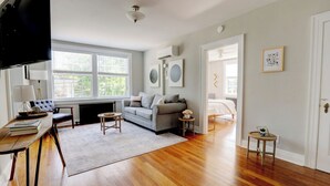 A spacious living room with hardwood flooring, a grey sofa, a coffee table, and a TV. - Historic Building/Walkable to Dtown/Central (Frankfort)