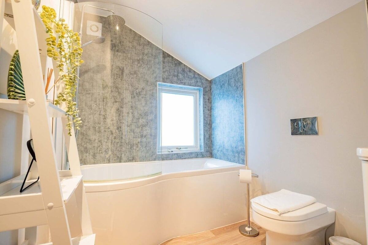 Ein modernes Badezimmer mit einer freistehenden Badewanne, einem Fenster und einer Toilette.
