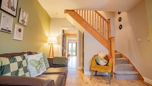 Ein Wohnzimmer mit einer Holztreppe, einem Sofa mit gemusterten Kissen und einem Sessel.