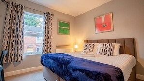 Ein Schlafzimmer mit Bett, Vorhängen, Heizkörper und Bildern an der Wand.