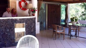Una encimera de piedra con un letrero que dice 'Free WiFi Zone', una puerta de madera y un patio con una silla blanca y una mesa de madera.