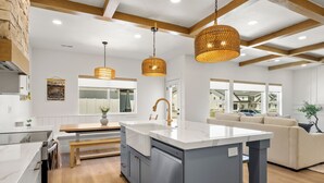 Een moderne keuken met een centraal eiland, houten balken en hanglampen.