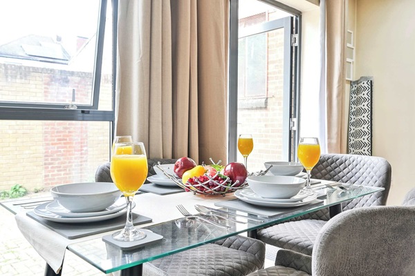 Glass dining table for four beside the patio doors, laid with crockery and glassware