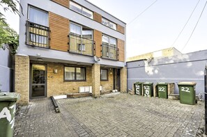 Een woongebouw met twee verdiepingen, een bakstenen gevel, een balkon en een geplaveid binnenterrein.