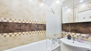 Une salle de bain moderne équipée d’une baignoire, d’une douche à parois de verre et d’un lavabo avec des articles de toilette.