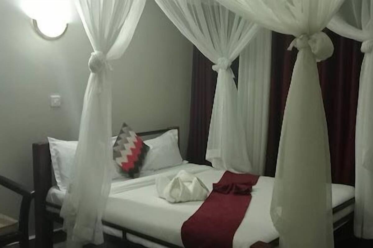 Una habitación de hotel con una cama con dosel, una silla y una mesita de noche.