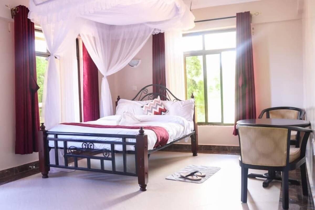 Un dormitorio con cama con dosel, una mesa y sillas.