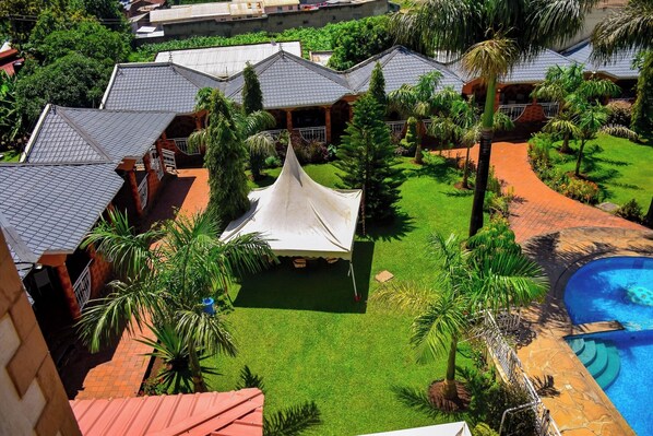 A resort with multiple buildings, a swimming pool, and a tent in the courtyard.