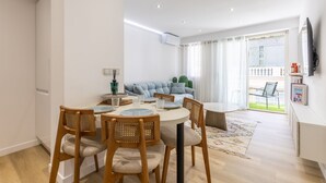 Ein modernes Wohnzimmer mit einer Couch, einem Esstisch mit Stühlen und einem an der Wand befestigten Fernseher.