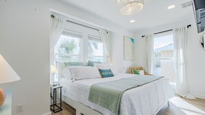 Une chambre à coucher avec un lit, une table de chevet, une lampe et une fenêtre avec des rideaux.