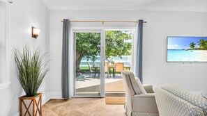 Ein Wohnzimmer mit einer Glasschiebetür, die auf eine Außenpatio mit Tisch und Stühlen führt.