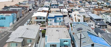 A coastal residential area with houses, a beach, and a clear sky.