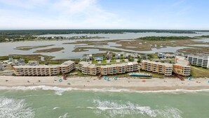 A coastal hotel with multiple buildings, a beach, and a bay.