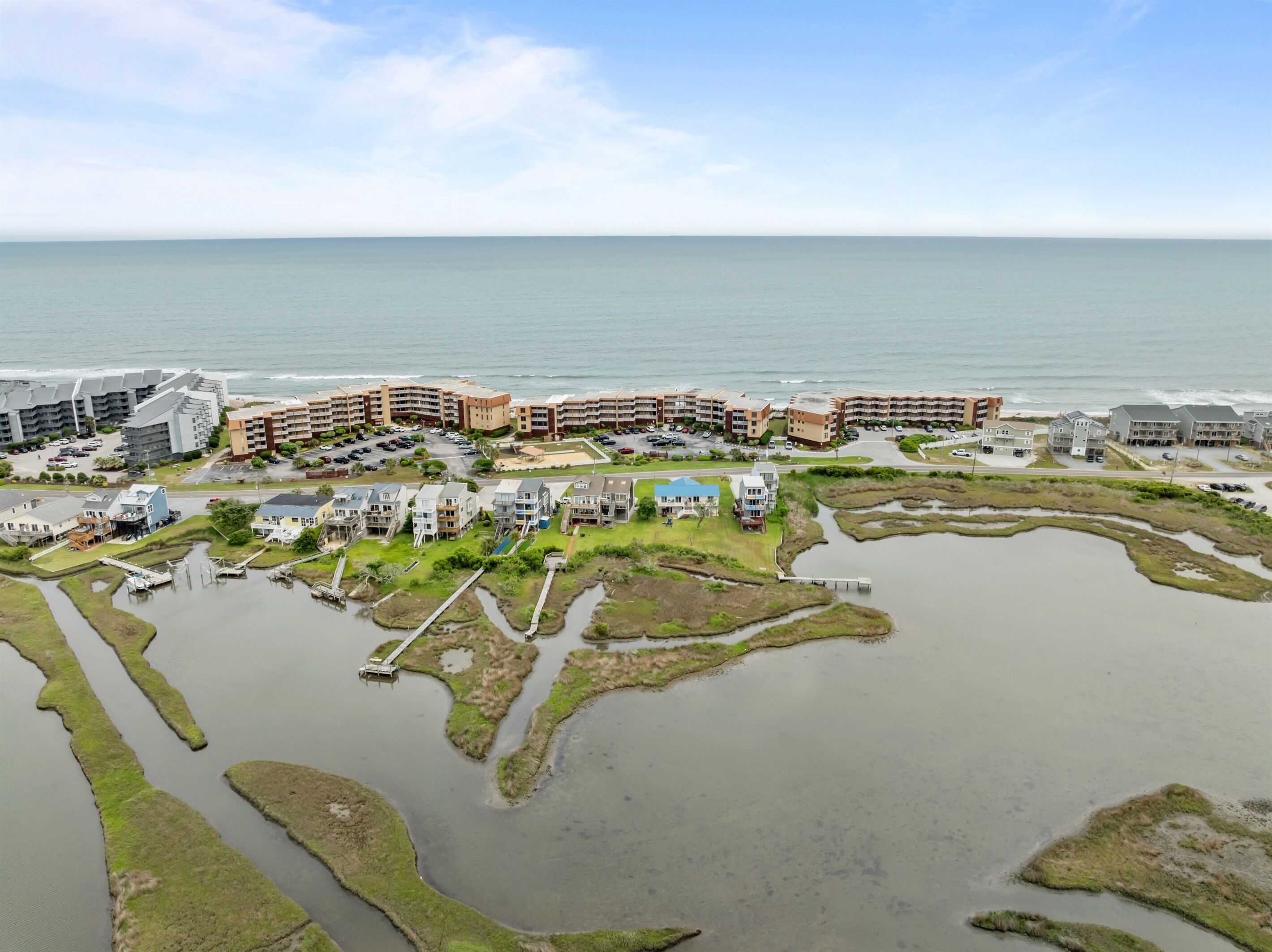 An aerial view of a coastal residential area with multiple apartment buildings, a marina, and a beach.