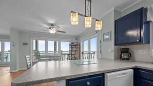 A kitchen with a granite countertop, dark blue cabinets, a ceiling fan, and a coffee maker.