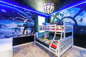 A bunk bed with a Star Wars-themed wall mural, a hanging spherical light fixture, and a window with a view of the sky.