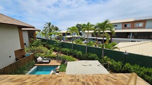 A pool area with a wooden deck, lounge chairs, and a small pool. - Casa Marluá (Camacari)