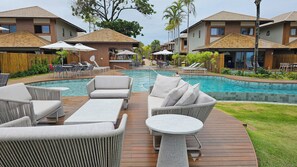 A resort with a swimming pool, lounge chairs, and wooden deck furniture. - Casa Marluá (Camacari)