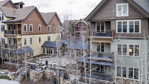 A residential area with multi-story houses, a stone pathway, and a small bridge. - Steps to Lifts, Peak 9, Main Street Balcony, Lounge Pool Water House 5204 by Avantstay (Breckenridge)