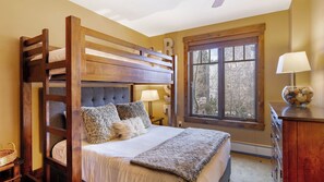 A bunk bed with a headboard, two pillows, a bedside lamp, and a window with a view. - Steps to Lifts, Peak 9, Main Street Balcony, Lounge Pool Water House 5204 by Avantstay (Breckenridge)