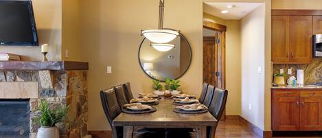 Un comedor con chimenea de piedra, un espejo grande y una cocina moderna con armarios de madera.
