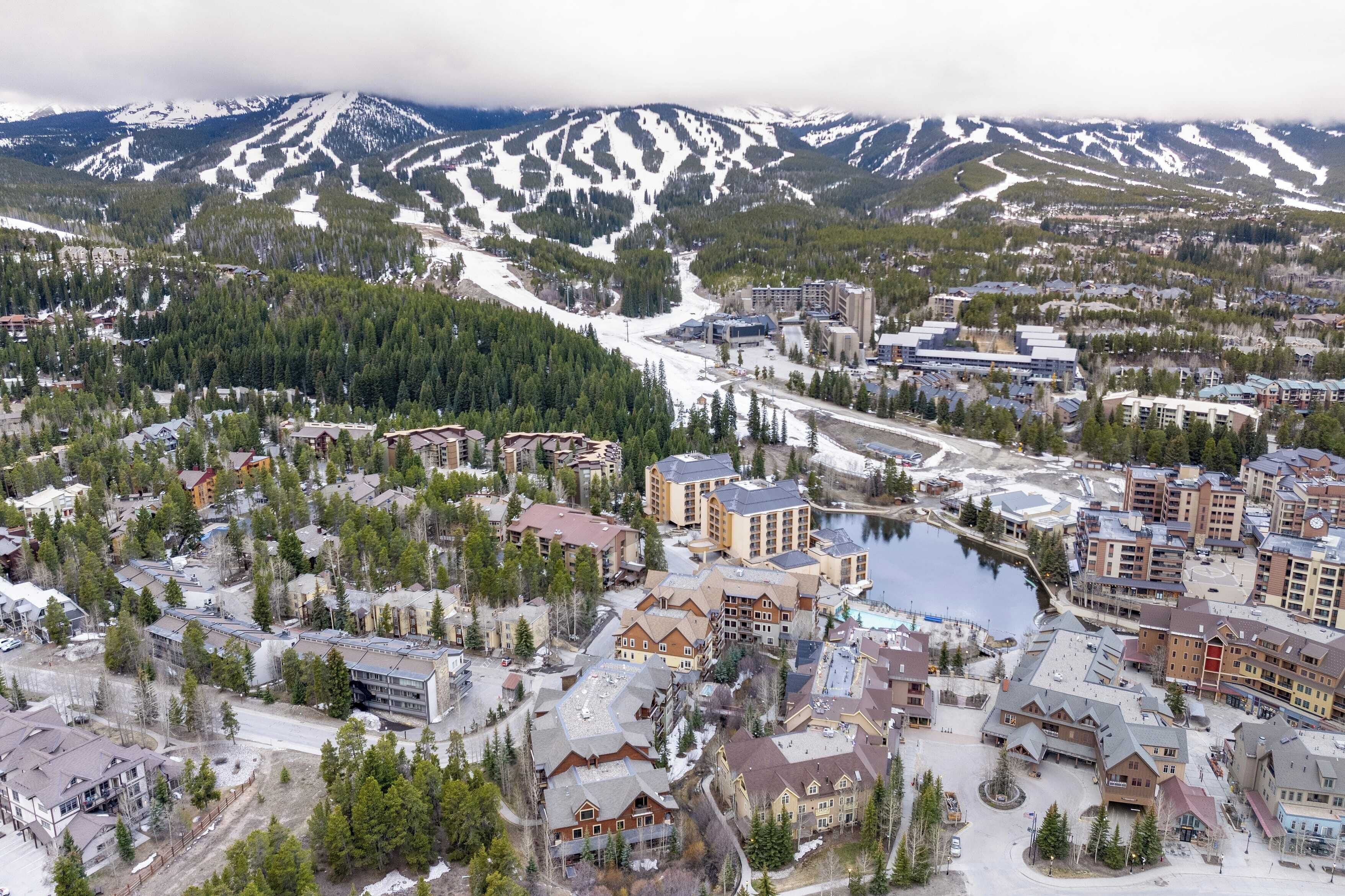A town with buildings, roads, and a lake surrounded by mountains.