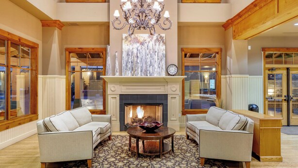 A spacious living room with a fireplace, two sofas, a chandelier, and large windows. - Steps to Lifts, Peak 9, Main Street Balcony, Lounge Pool Water House 5204 by Avantstay (Breckenridge)