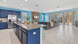 Een moderne keuken met donkerblauwe kastjes, een granieten aanrechtblad en roestvrijstalen apparatuur.