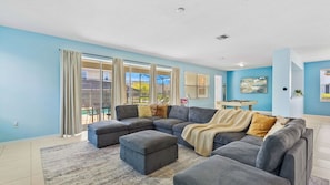 Ein Wohnzimmer mit Ecksofa, Hocker und Billardtisch.