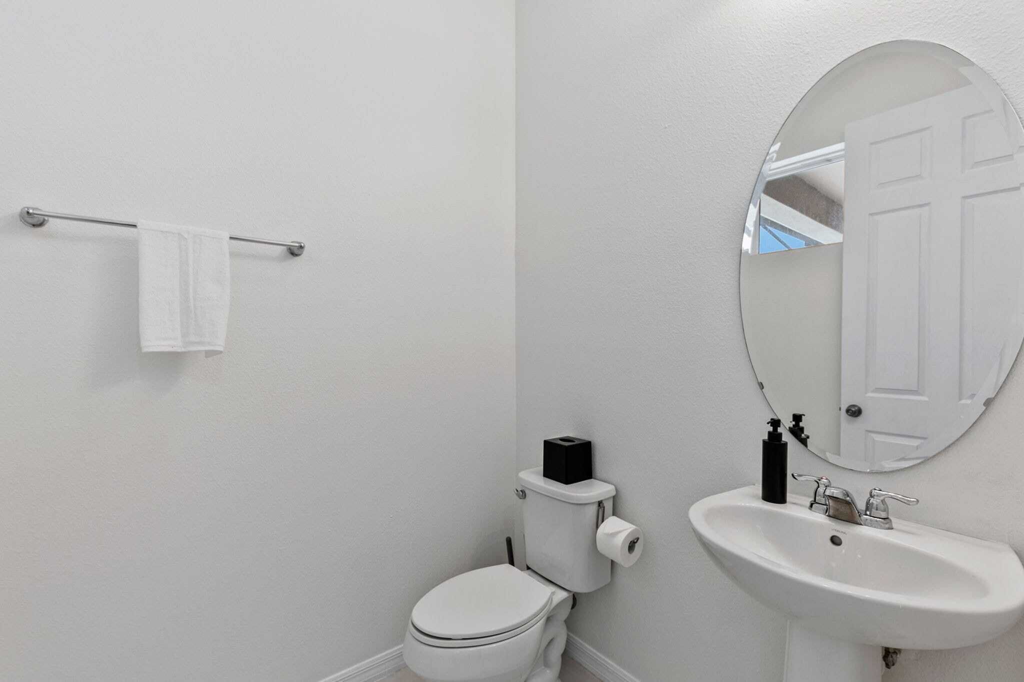 A bathroom with a toilet, sink, and mirror.