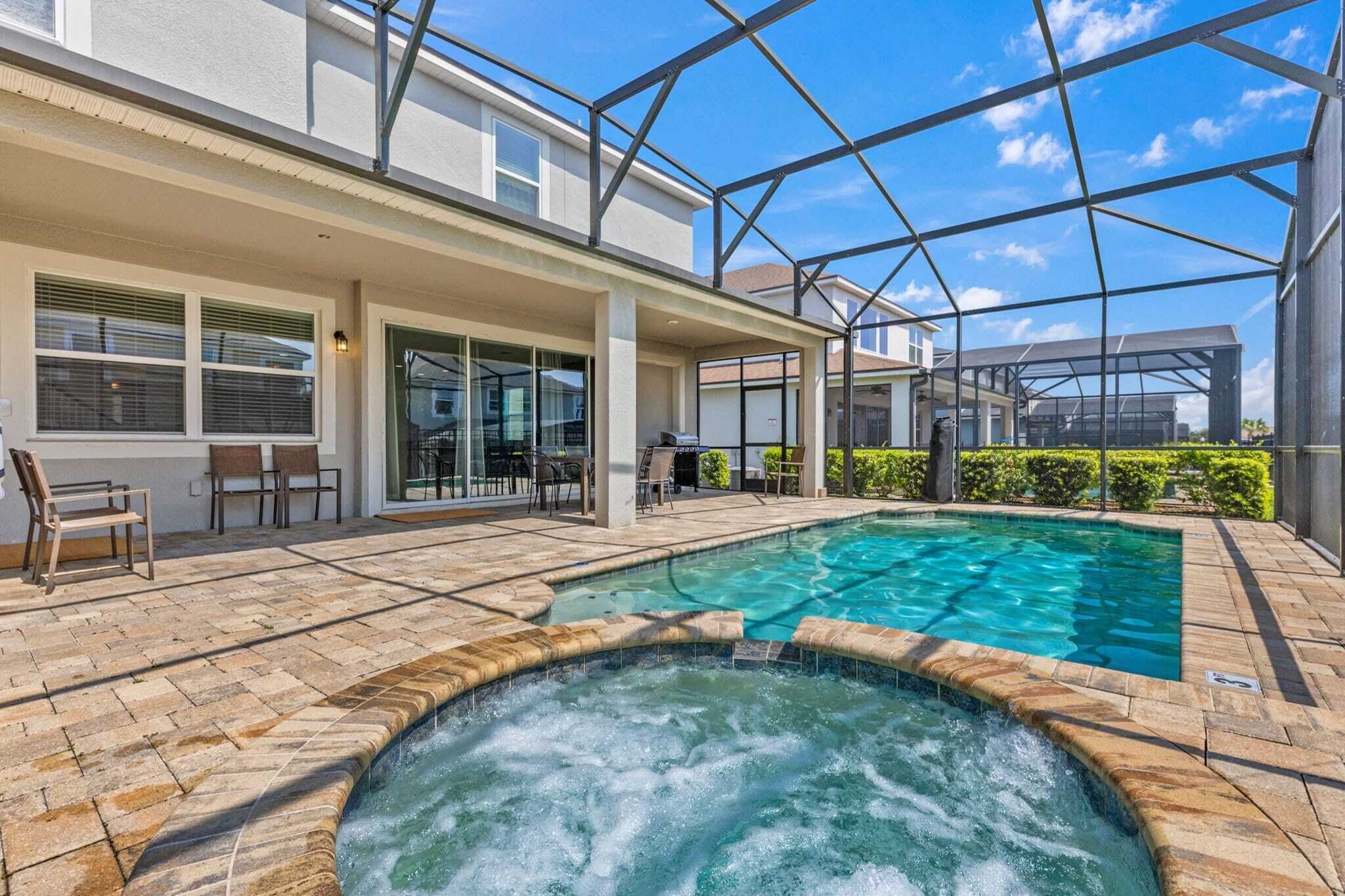 A swimming pool with a hot tub, outdoor seating, and a covered patio area.