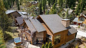 A modern lodge with a large deck, a hot tub, and a stone fireplace. - Creekside Lodge | Hot Tub | Ski-Out | Pool Table (Panorama)