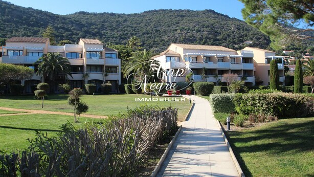 A residential building with multiple balconies, a well-maintained lawn, and a pathway leading to the entrance.