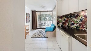 A modern kitchen with white cabinets, a black countertop, and a colorful leaf-patterned backsplash.