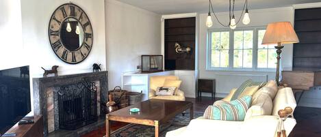 A living room with a fireplace, a sofa, a coffee table, and a large wall clock.