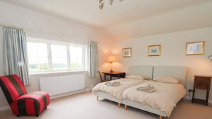 A bedroom with a bed, a chair, a lamp, and a window. - Higher Park Farm (Macclesfield)