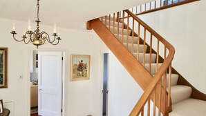 A staircase with wooden railings leading to a landing, a chandelier, and a framed picture on the wall. - Higher Park Farm (Macclesfield)