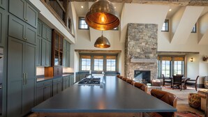 A spacious kitchen with a large island, dark cabinetry, and a stone fireplace. - Rustic Luxury Barn Retreat in Pray, Montana – Family & Pet Friendly (Livingston)