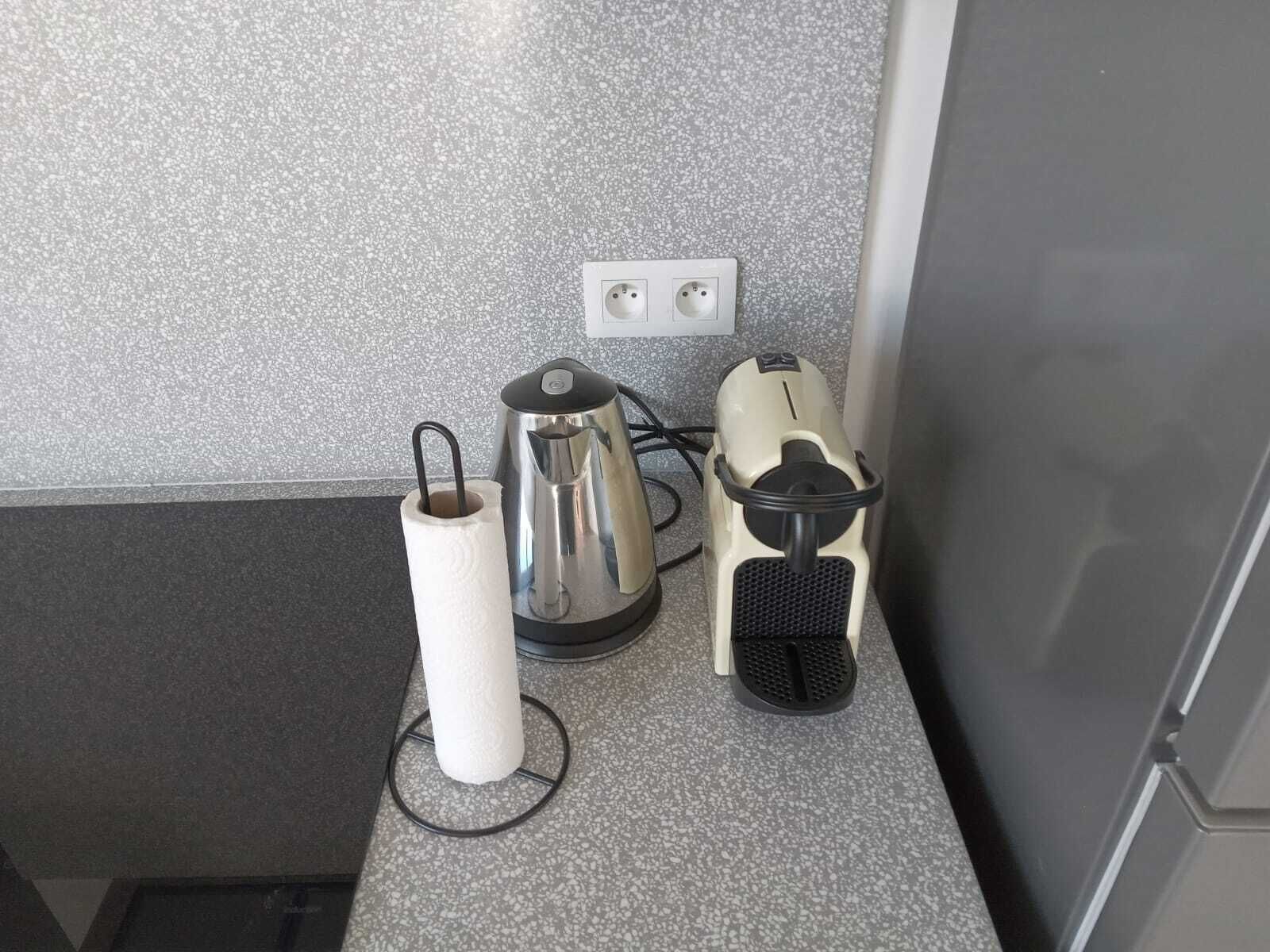 Una encimera de cocina con un hervidor, una tostadora y un dispensador de toallas de papel.