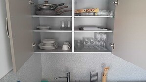 A kitchen with a built-in cabinet containing plates, bowls, glasses, and a frying pan. - 1 bedroom apartment in marigot (Marigot)