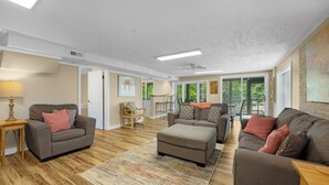 A spacious living room with a sofa set, a dining area, and a view of the outdoors.